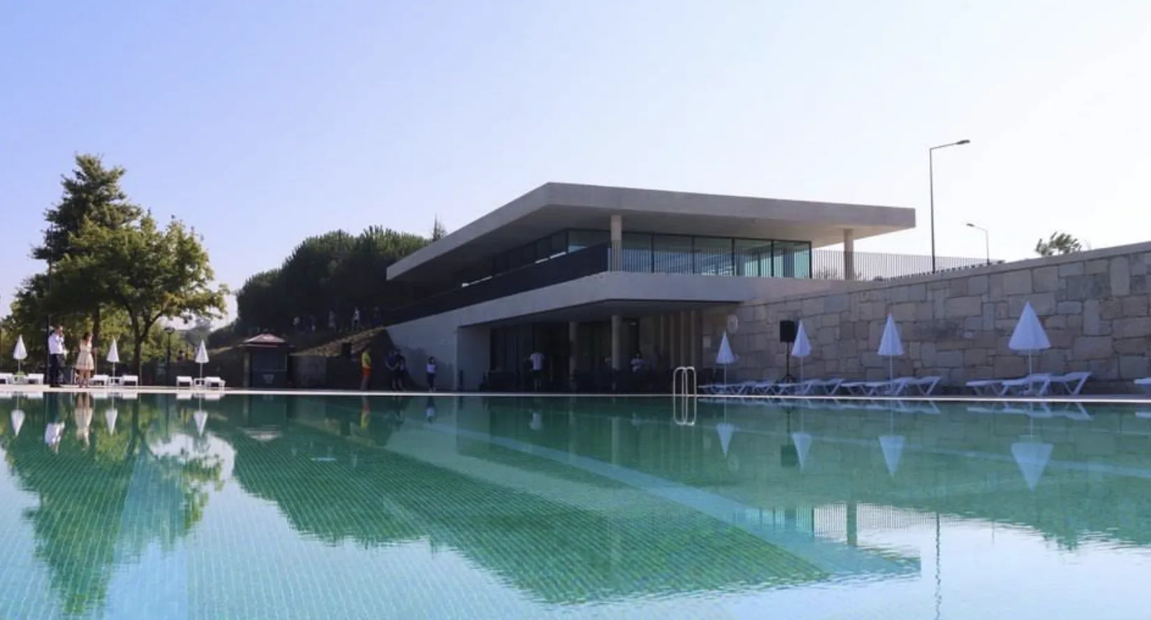 Piscina Verde in Paredes, with the building and loungers reflected in the water