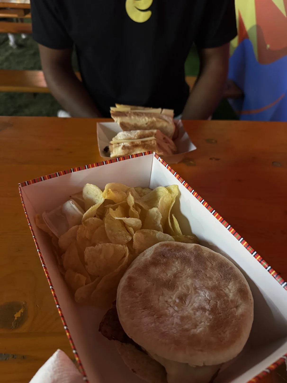Sandwich and fries on a wooden table inside the festival