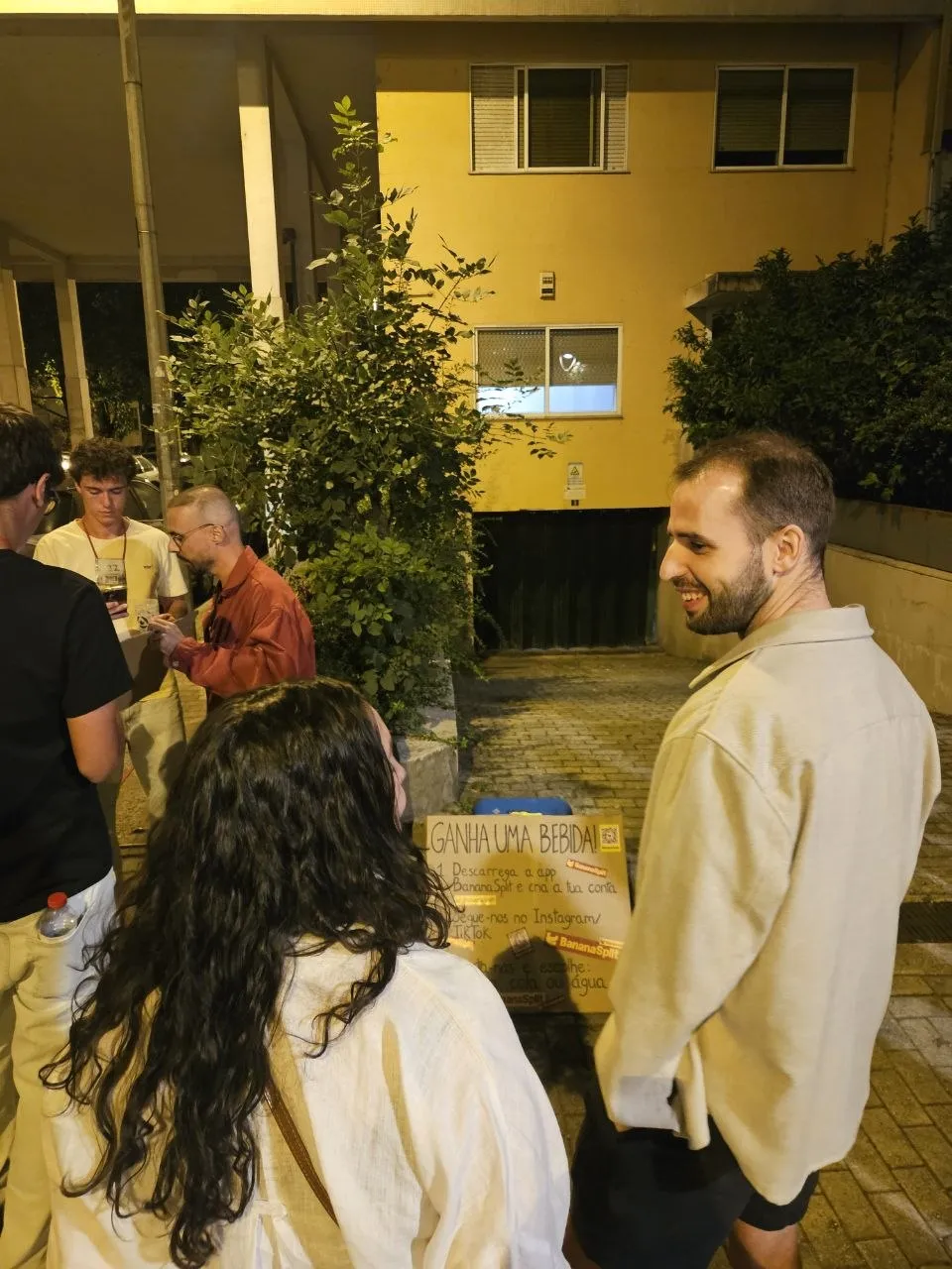 Ana and Henrique next to the BananaSplit sign, in the street at night