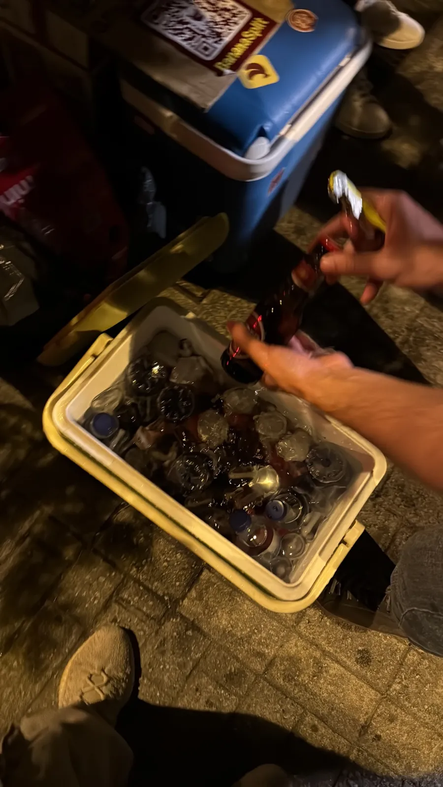 An open cooler with bottles on ice and a hand pulling out a drink