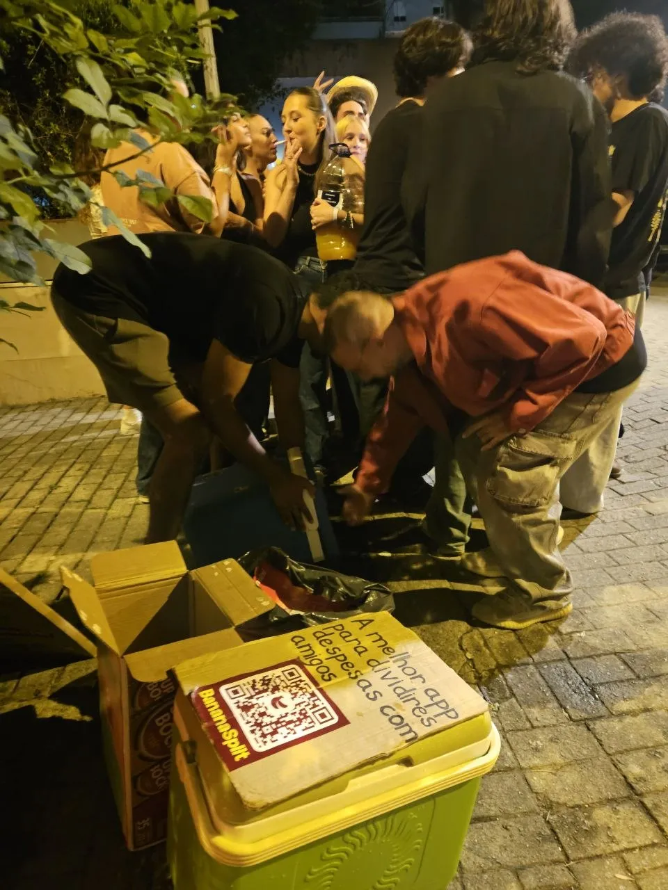 Two BananaSplit team members leaning over the coolers, serving drinks in the middle of a group