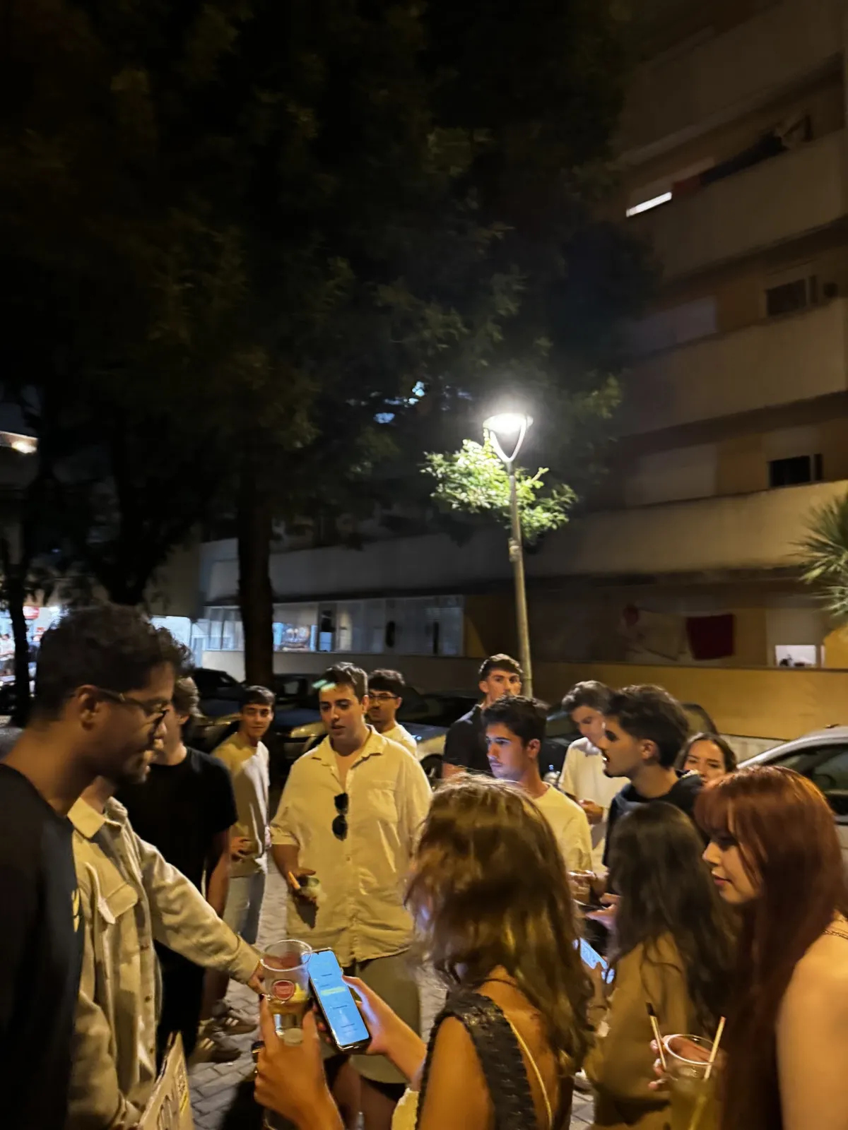 A group of students holding cups around the BananaSplit team, in a packed street at night