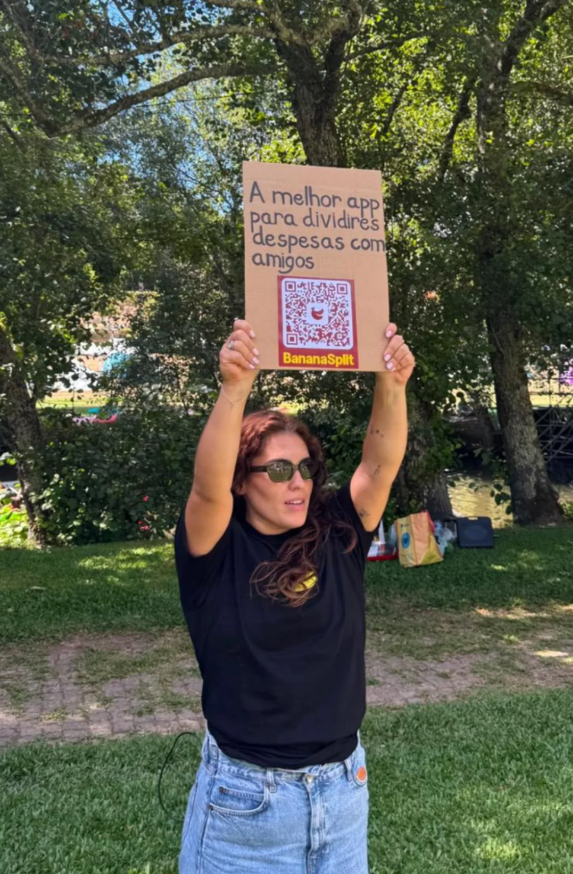 Woman holding a handmade BananaSplit QR code sign above her head at an outdoor event